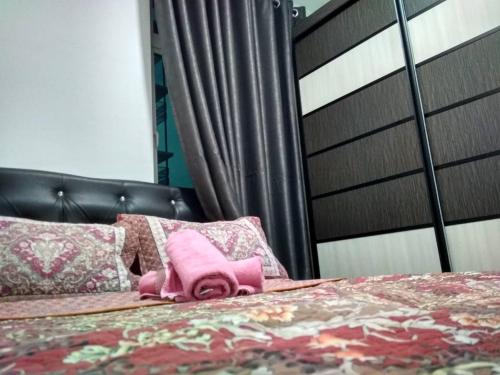 a pink toy animal sitting on top of a bed at Wellsuits Putrajaya in Putrajaya