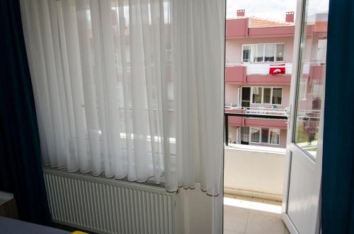 a window with white curtains and a view of a building at Çanakkale Venüs Pansiyon in Canakkale