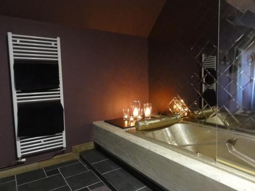 La salle de bains est pourvue d'une baignoire avec des bougies et d'une fenêtre. dans l'établissement Le Manoir des Tuileries, à Rouffilhac