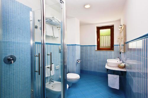 a blue bathroom with a toilet and a sink at Punta Campanella Resort & Spa in Massa Lubrense