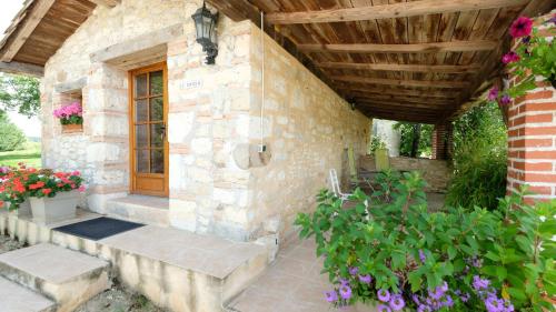 a stone house with a wooden door and some flowers at Domaine Les Miquels in Castelnau-de-Montmiral