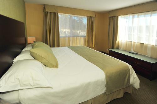 a bedroom with a large white bed with a window at Ramada by Wyndham Williams Lake in Williams Lake