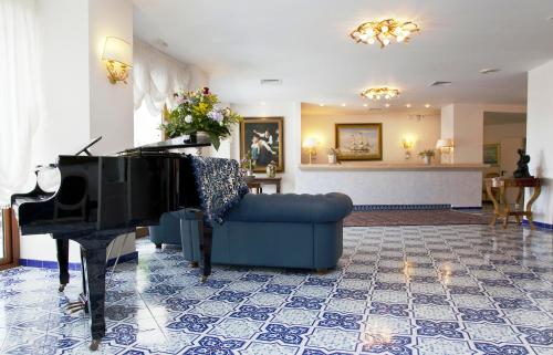 a living room with a blue couch and a piano at Punta Campanella Resort & Spa in Massa Lubrense