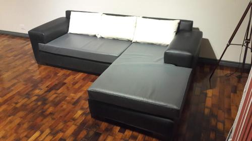 a black leather couch with two white pillows on it at Departamento España in Mendoza