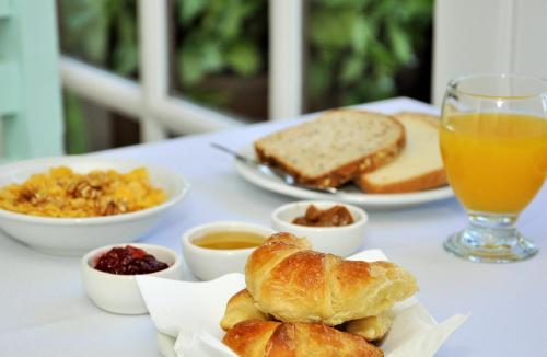 a table with breakfast foods and a glass of orange juice at Posada de las Aguilas Hotel Boutique in Ezeiza