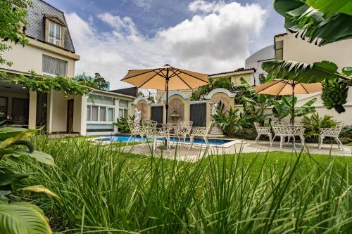 a patio with chairs and umbrellas in front of a house at Hotel San Carlos in Guatemala