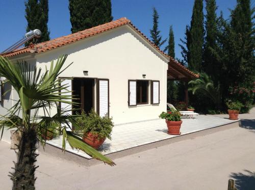 a small white house with potted plants in front of it at Gialova garden bungalow in Gialova