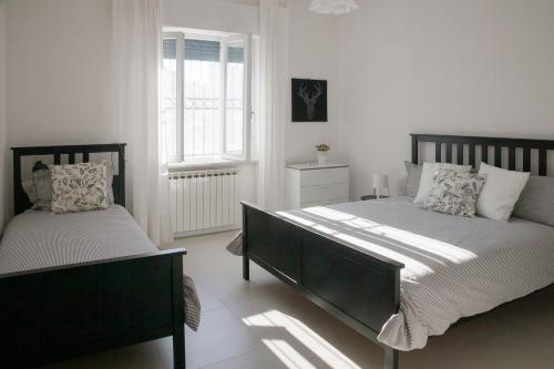 sypialnia z 2 łóżkami i oknem w obiekcie Flora Home w mieście Marina di Carrara