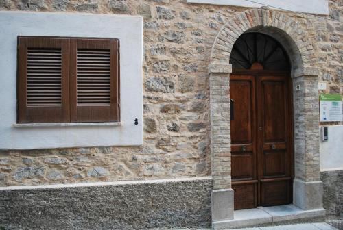 a stone building with a wooden door and a window at La Mariposa in Nova Siri