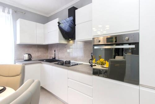 a kitchen with white cabinets and a stove top oven at Mandalina Suite in Šibenik