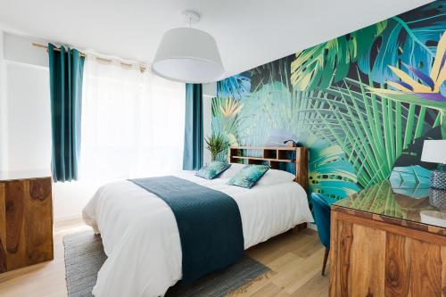 a bedroom with a large bed with a tropical wallpaper at Naeva Feng Shui in Strasbourg