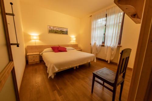 a bedroom with a bed and a chair and a window at La Casa in Collina in Alba