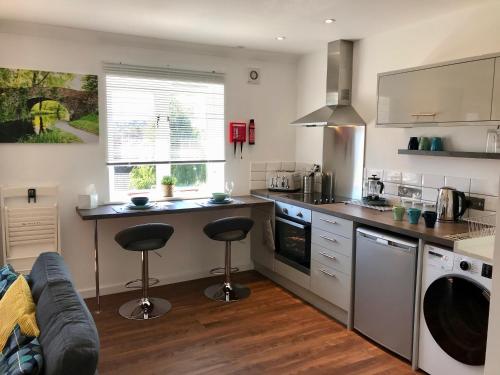 a kitchen with a counter and two bar stools at Upper Highview - Self Catering Apartment, fpventures Stroud in Stroud