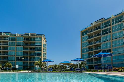 a swimming pool with blue umbrellas and buildings at Blue Residences in Palm-Eagle Beach
