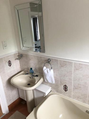 a bathroom with a sink and a mirror and a tub at Dysart Sea View Apartment in Dysart