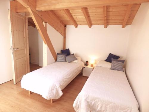 two beds in a room with wooden ceilings at Ihi-Toki in Saint-Pée-sur-Nivelle