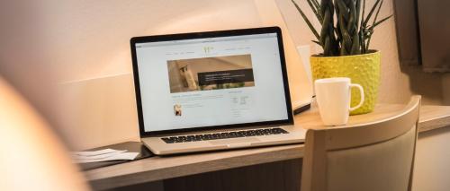 a laptop computer sitting on a desk with a cup of coffee at Hotel Carlton Mayfair in Düsseldorf