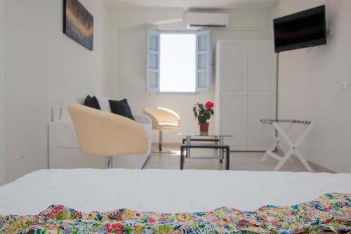 a bedroom with a bed and chairs and a television at Luna Rossa Santorini in Imerovigli