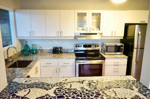 a kitchen with white cabinets and a granite counter top at Oceania Villas in Culebra