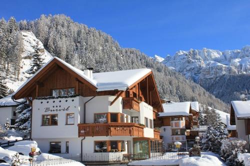 a building in the snow with mountains in the background at Apartments Burvel in Selva
