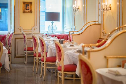 a dining room with tables and chairs with red seats at Schlosshotel Römischer Kaiser in Vienna