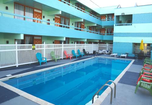 a swimming pool in a hotel with chairs and a building at Beachside Resort in Wildwood