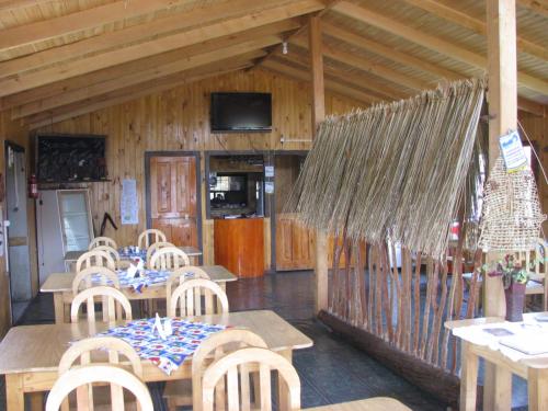 un restaurante con mesas y sillas de madera y TV en Cabanas Neptuno en Quellón