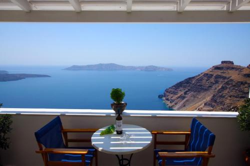 a table and chairs with a view of the ocean at Hotel Mylos in Firostefani