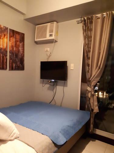 Schlafzimmer mit einem Bett und einem Flachbild-TV in der Unterkunft Eiffel Suite Chateau Elysee near NAIA Airport in Manila
