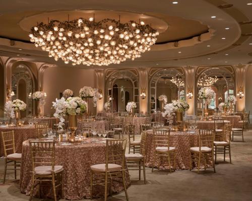 ロサンゼルスにあるThe Beverly Hills Hotel - Dorchester Collectionのテーブルと椅子、シャンデリアのある宴会場