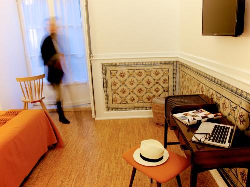a room with a bed and a table with a hat on it at Hall Chiado in Lisbon