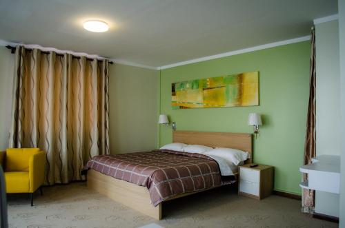 a bedroom with a bed and a yellow chair at Gess Hotel in Paramaribo