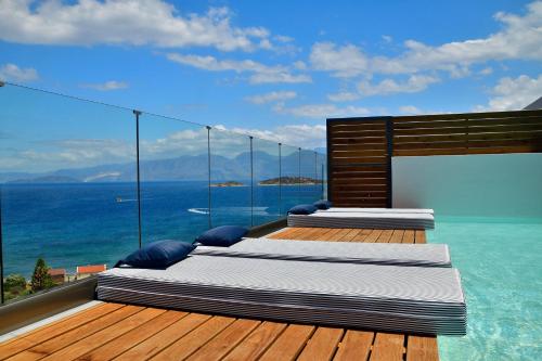 three beds on a deck with a view of the ocean at Meliti Hotel (Adults Only) in Agios Nikolaos