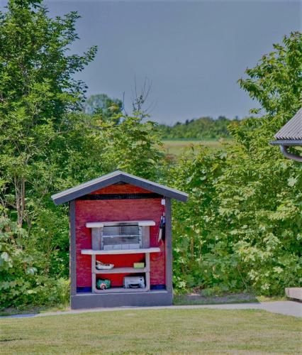 a small red dog house in the grass at Ølholm Cottage in Stege