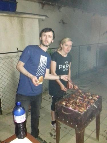 a man and woman standing next to a table with food at Makos Guest House in Kutaisi