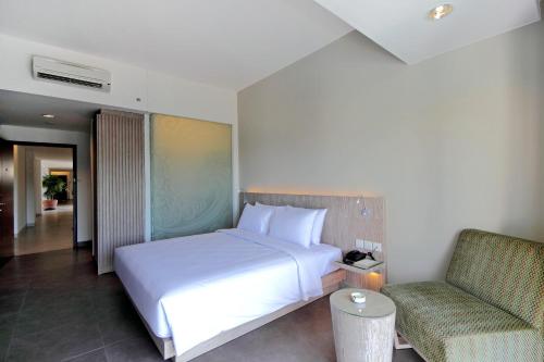 a bedroom with a white bed and a chair at Hotel Santika Siligita Nusa Dua in Nusa Dua
