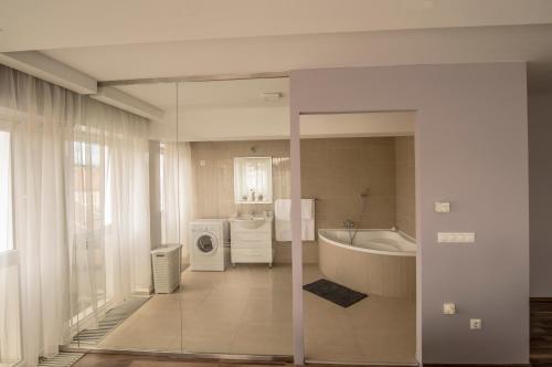 a bathroom with a tub and a washing machine at Unicorniselit Apartmanok in Eger