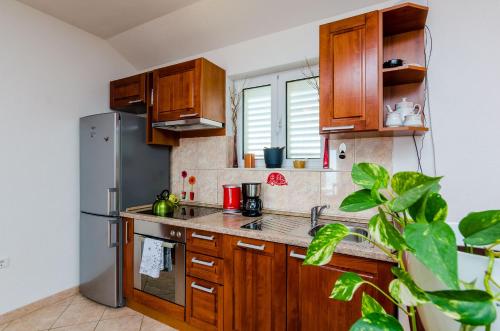 Una cocina con gabinetes de madera y un refrigerador de acero inoxidable. en Apartments Joy, en Cavtat