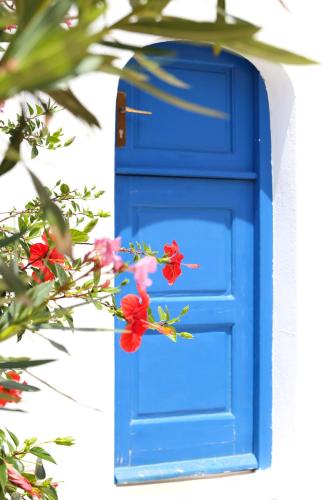 a blue door with red flowers in front of it at Baba Houlakia in Houlakia