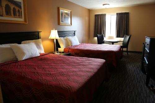 Habitación de hotel con 2 camas, mesa y sillas en Americas Best Value Inn Kelso en Kelso