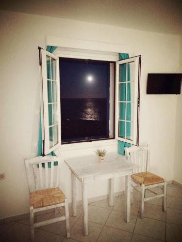 a table and two chairs in a room with a window at Litus Studios Syros in Megas Yialos-Nites