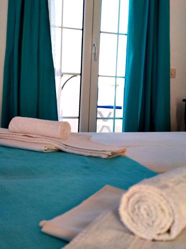 two towels are laying on a bed with blue curtains at Litus Studios Syros in Megas Yialos-Nites