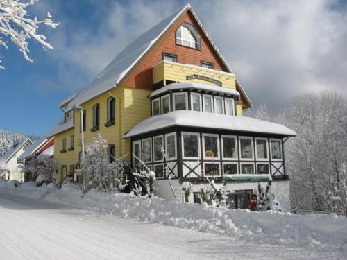een groot geel huis met sneeuw op de grond bij Komfortferienwohnung Heuboden in Sankt Andreasberg