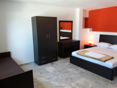 a bedroom with a bed and a dresser and a mirror at Manos Apartments in Agios Nikolaos