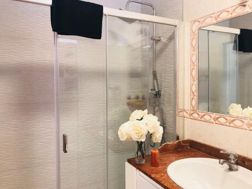 a bathroom with a sink and a shower with white flowers at Apartamento Las Veronicas in Arona