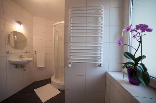 baño con ducha, lavabo y un jarrón de flores en Rezydencja Pod Ochorowiczówką B&B, en Wisła