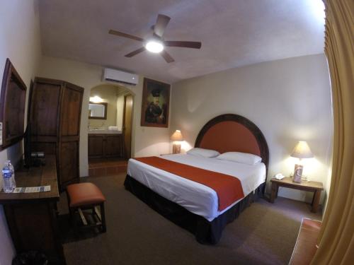 Habitación de hotel con cama y ventilador de techo. en Club Cantamar Beach Hotel & Marina, en La Paz