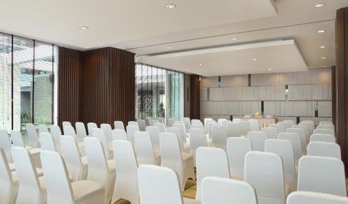 a conference room with white chairs and a projection screen at Hotel Santika Siligita Nusa Dua in Nusa Dua
