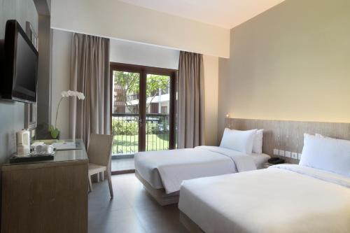 a hotel room with two beds and a television at Hotel Santika Siligita Nusa Dua in Nusa Dua