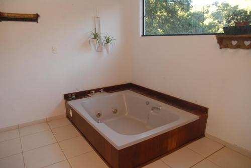 a large bath tub in a room with a window at Pousada Mirante do Penedo in Penedo